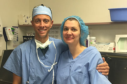 Anne Peled, MD and her husband, Ziv Peled, MD standing in the OR